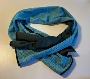 Ein kühlendes Handtuch in blau und schwarz liegt auf dem Tisch.